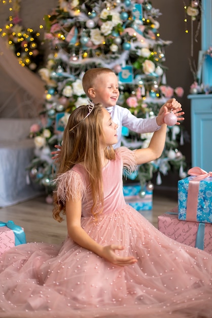 Bambina sveglia in un vestito rosa con suo fratello a Natale