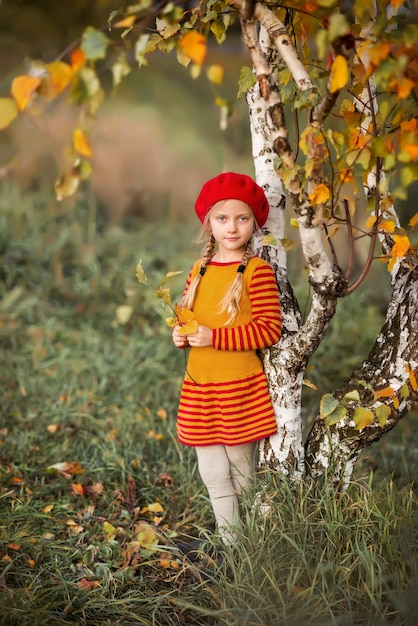 Bambina sveglia in vestiti a maglia nella sosta di autunno