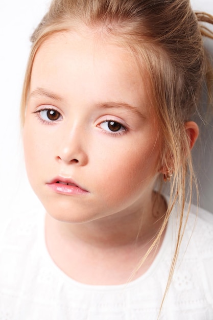 Bambina sveglia in vestito bianco sopra priorità bassa bianca