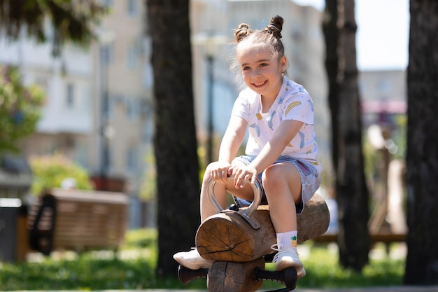 Bambina sveglia in vestito blu che gioca nel parco divertendosi all'aperto