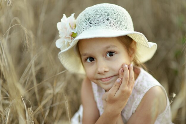 Bambina sveglia nel campo di grano estivo sopra il tramonto