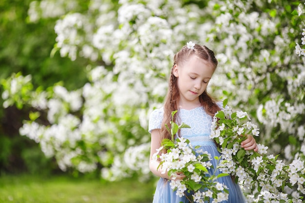 Bambina sveglia nel giardino di fioritura di melo alla molla