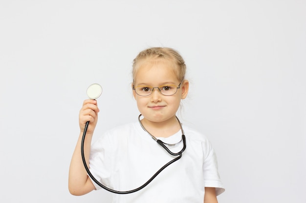 Bambina sveglia vestita come un medico che guarda l'obbiettivo con un sorriso allegro