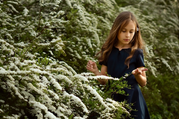 Bambina sveglia vicino ai bei cespugli di fioritura bianchi