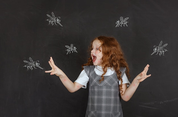 Bambina triste che ha paura delle punture di zanzare che volano intorno a lei.