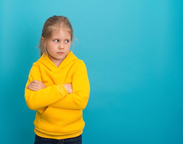 Bambina triste offesa con le braccia incrociate che guarda da parte per copiare lo spazio