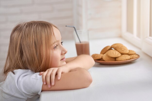 Bambina vaga con i biscotti sul davanzale della finestra