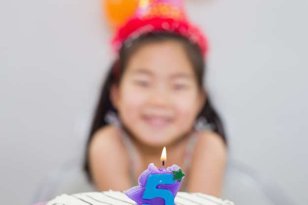 Bambina vaga con la candela accesa sulla torta di compleanno