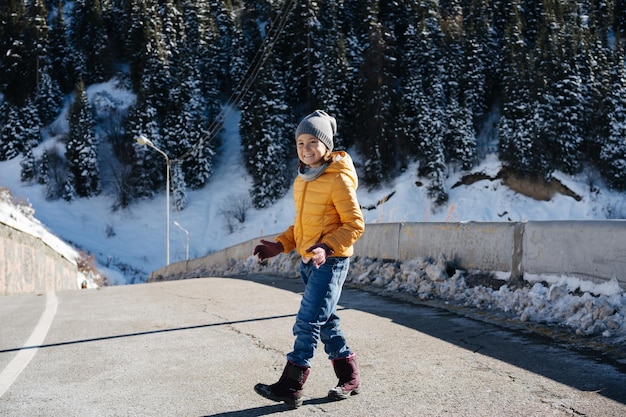 Bambina vestita calorosamente su uno stretto brige di auto di montagna in inverno