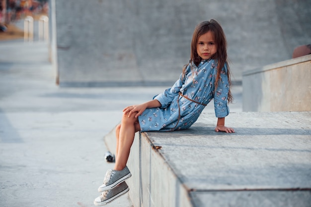 Bambina vestita di blu in posa in città quando si appoggia sulla rampa