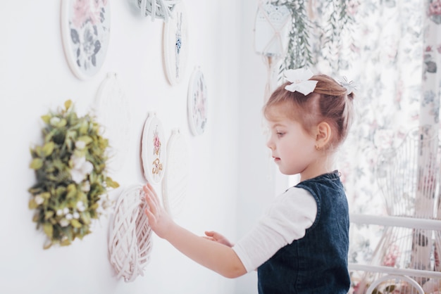 Bambina vicino allo specchio. Una piccola fashionista in camera da letto