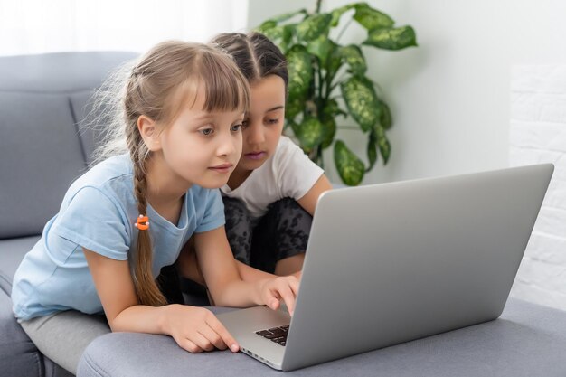 Bambine a casa con laptop, videochat con i loro amici.