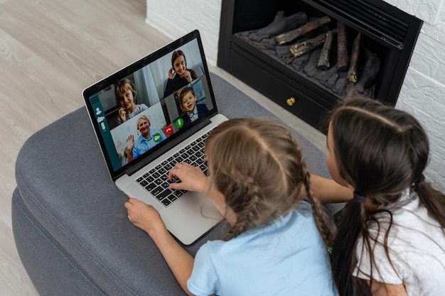 Bambine a casa con laptop, videochat con i loro amici.