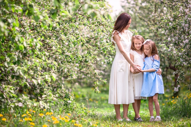 Bambine adorabili con la giovane madre nel giardino di fioritura della ciliegia il bello giorno di molla