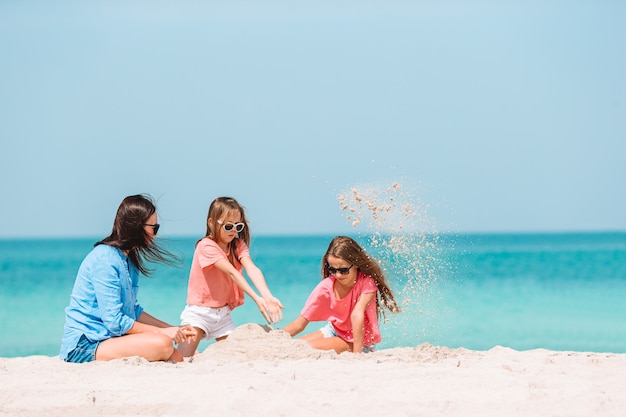 Bambine adorabili e giovane madre sulla spiaggia bianca tropicale