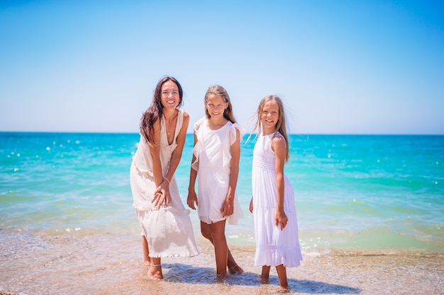 Bambine adorabili e giovane madre sulla spiaggia bianca tropicale