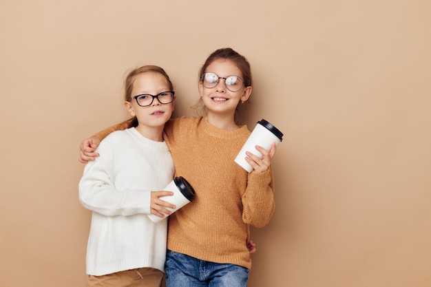 Bambine che abbracciano insieme il vetro con la bevanda