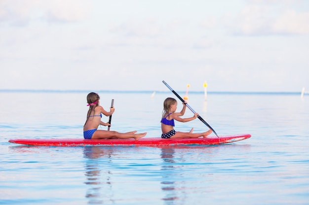 Bambine che nuotano sul surf durante le vacanze estive