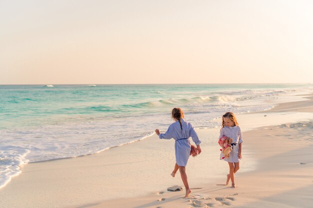 Bambine divertendosi alla spiaggia tropicale che gioca insieme alle acque basse