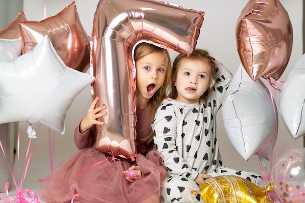 Bambine in abito da sera guardando fuori da un palloncino a forma di sette