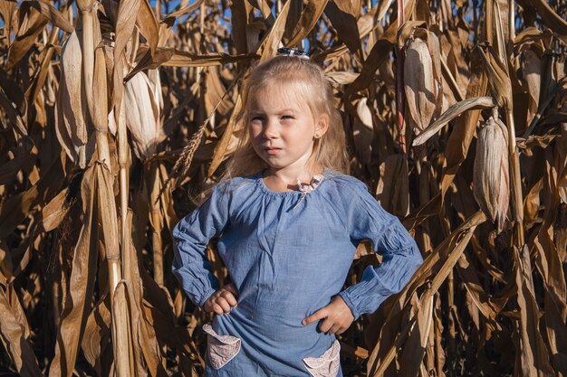 Bambine in un vestito si trova in un campo di mais secco