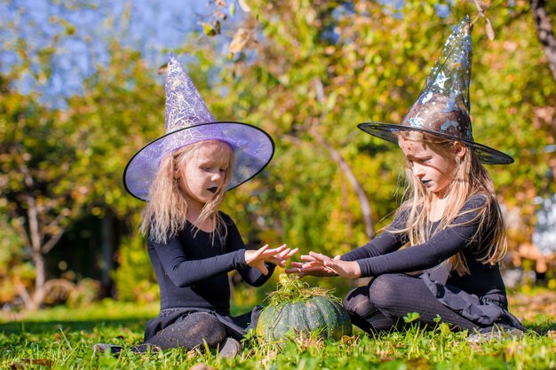 Bambine sveglie che lanciano un incantesimo su Halloween in costume da strega