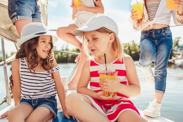 Bambini a bordo di yacht sul mare bevono succo d'arancia