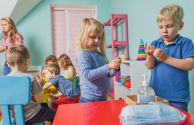 Bambini adorabili dell'asilo che si puliscono le mani con un disinfettante