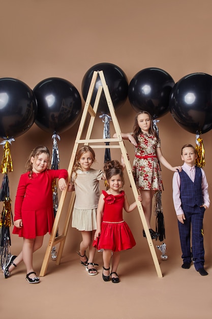 Bambini alla moda in abiti da sera e costumi che celebrano il primo giorno di scuola.