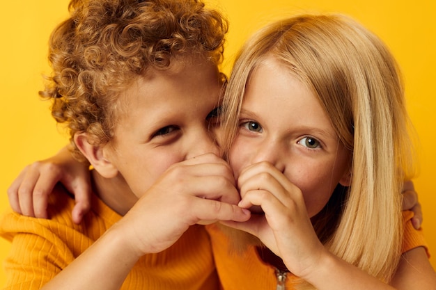 Bambini alla moda svegli in magliette gialle che stanno fianco a fianco le emozioni dell'infanzia hanno isolato il fondo