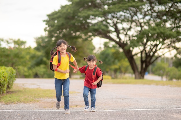 Bambini asiatici carini che si tengono per mano mentre vanno a scuola