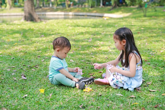 Bambini asiatici che giocano insieme nel giardino prato verde. La sorella gioca con il suo fratellino all&#39;aperto.