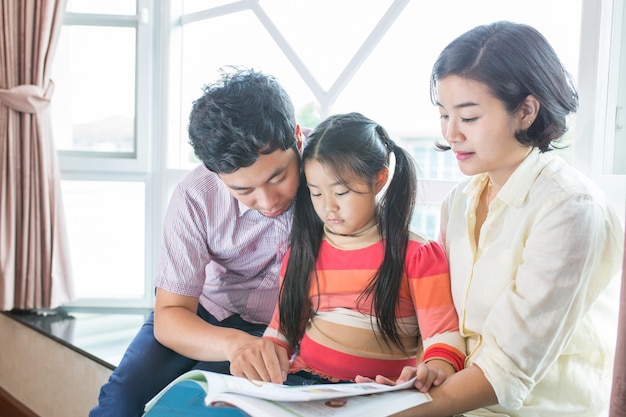 Bambini asiatici che leggono il libro in soggiorno.