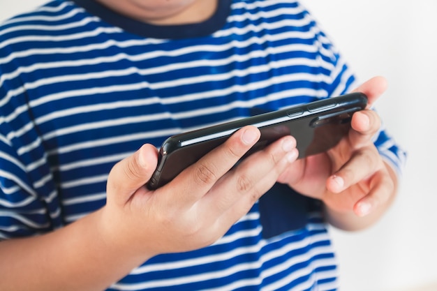 Bambini asiatici grassi che giocano su smartphone