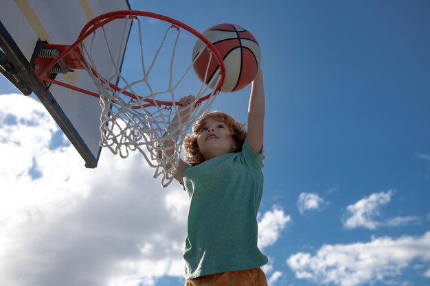 Bambini attivi che si divertono a giocare all'aperto con il basket all'aperto nel parco giochi