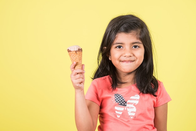 Bambini carini indiani o asiatici che mangiano gelato o barretta di mango o caramelle. Isolato su sfondo colorato