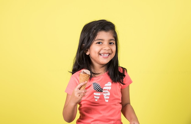 Bambini carini indiani o asiatici che mangiano gelato o barretta di mango o caramelle. Isolato su sfondo colorato