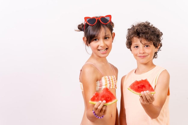 Bambini caucasici che mangiano un cocomero nel concetto di vacanza scolastica estiva di calore Sfondo bianco