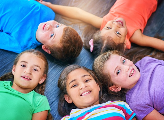 Bambini cerchio e ritratto sul pavimento alla scuola di sopra e felici per l'apprendimento legame e sviluppo Bambini diversità e istruzione raggrupparsi con gli amici e sorridere con solidarietà in classe
