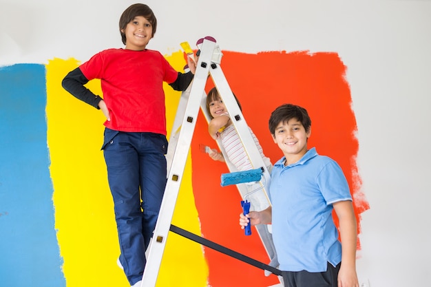 Bambini che aiutano a dipingere il muro a casa