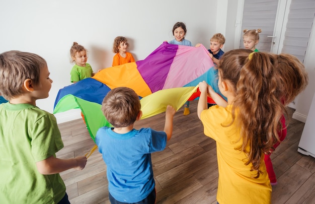 Bambini che allungano il paracadute colorato per divertenti giochi di squadra