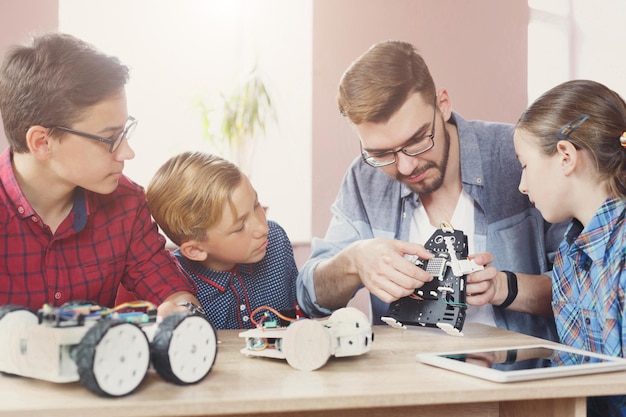 Bambini che creano robot con insegnante a scuola, educazione del gambo. Sviluppo precoce, educazione, fai da te, innovazione, concetto di tecnologia moderna