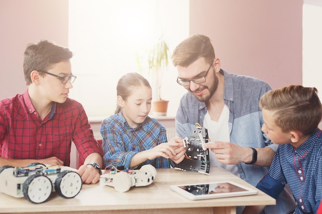 Bambini che creano robot con insegnante a scuola, educazione del gambo. Sviluppo precoce, educazione, fai da te, innovazione, concetto di tecnologia moderna