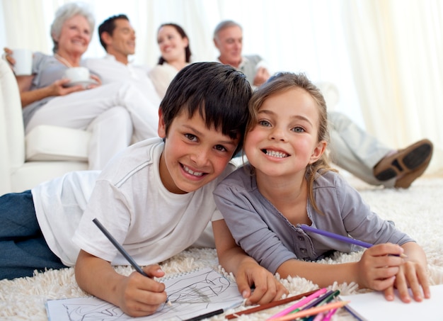 Bambini che dipingono sul pavimento con la loro famiglia nel divano