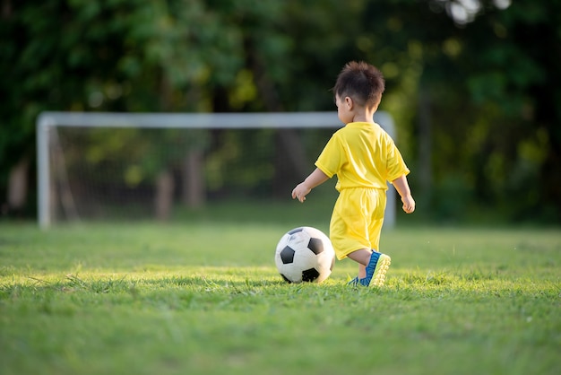 Bambini che giocano a calcio nel campo verde.