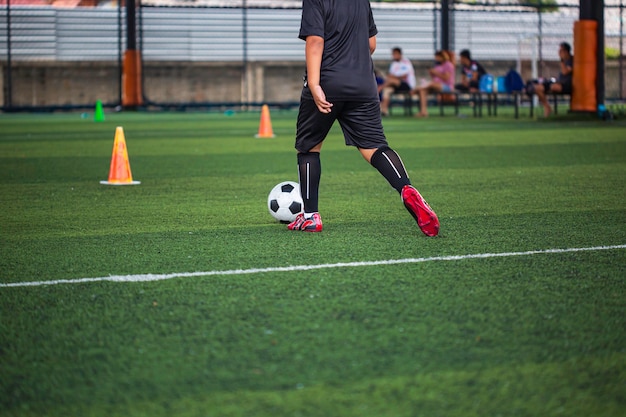 Bambini che giocano a cono di tattiche di controllo del pallone da calcio sul campo in erba con sfondo di allenamento Formazione dei bambini nel calcio