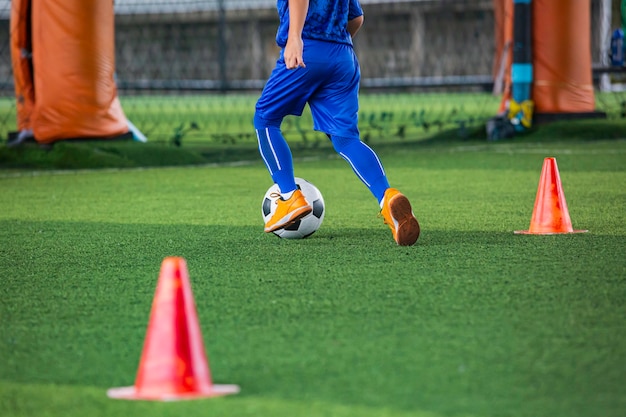 Bambini che giocano a cono di tattiche di controllo del pallone da calcio sul campo in erba con sfondo di allenamento Formazione dei bambini nel calcio