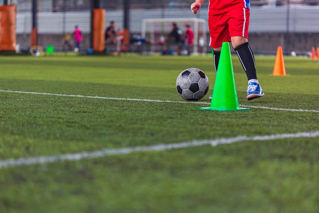 Bambini che giocano a cono di tattiche di controllo del pallone da calcio sul campo in erba con sfondo di allenamento Formazione dei bambini nel calcio