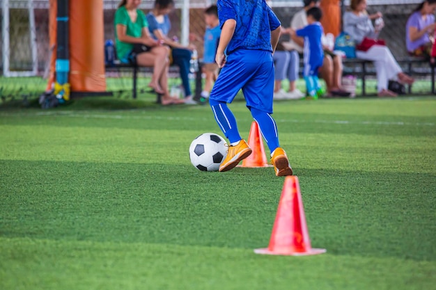 Bambini che giocano a cono di tattiche di pallone da calcio di controllo sul campo in erba con sfondo di formazione Allenare i bambini nel calcio