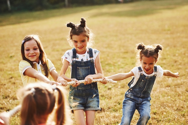 Bambini che giocano al tiro alla fune nel bellissimo prato al giorno di sole.